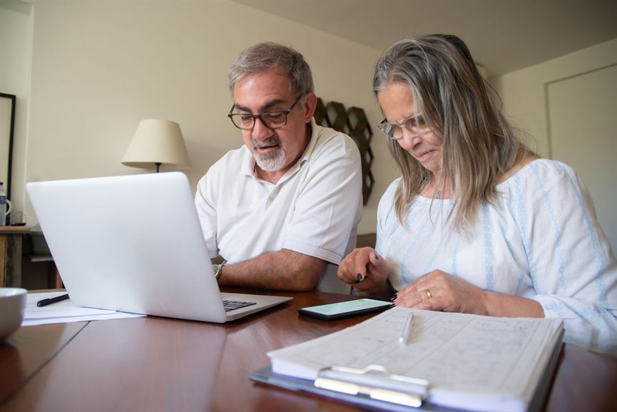 Couple at a desk planning a cruise on a laptop